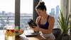 Woman reading protein supplement nutrition label at kitchen table