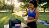 Fit black woman preparing layered protein powder shake in home gym