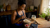 Black woman adding protein powder to oatmeal in kitchen