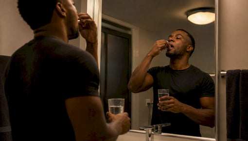Black male athlete taking night supplement capsule