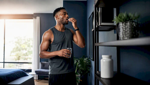 Fit black man taking supplement capsule in gym