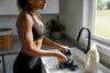 Fit Black woman hand-washing gym clothes