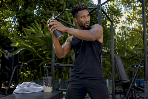 Black athlete shaking protein bottle in gym